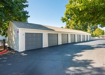 a row of garages in a parking lot with trees